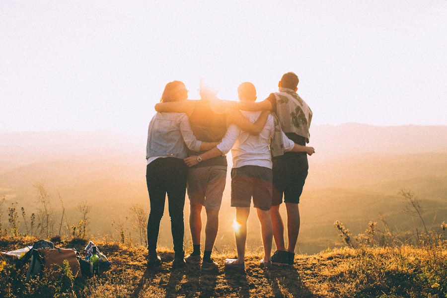 Groupe d'amis bras dessus bras dessous face au soleil couchant
